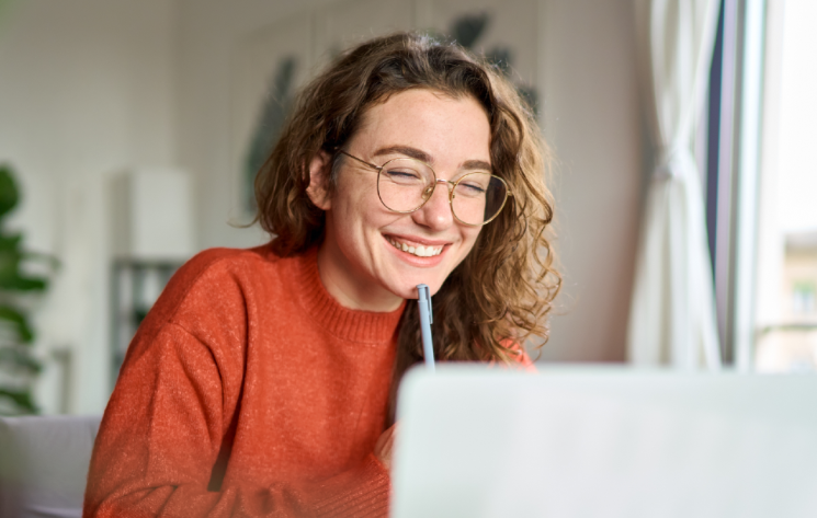 Woman wearing glasses looking at laptop screen and smiling